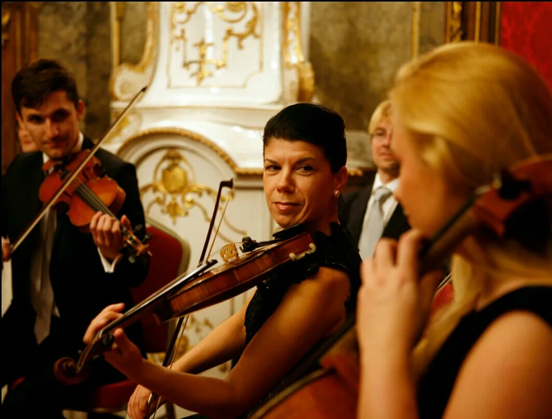The string players at close quarters mid-performance, a violinist looking up from her part.
