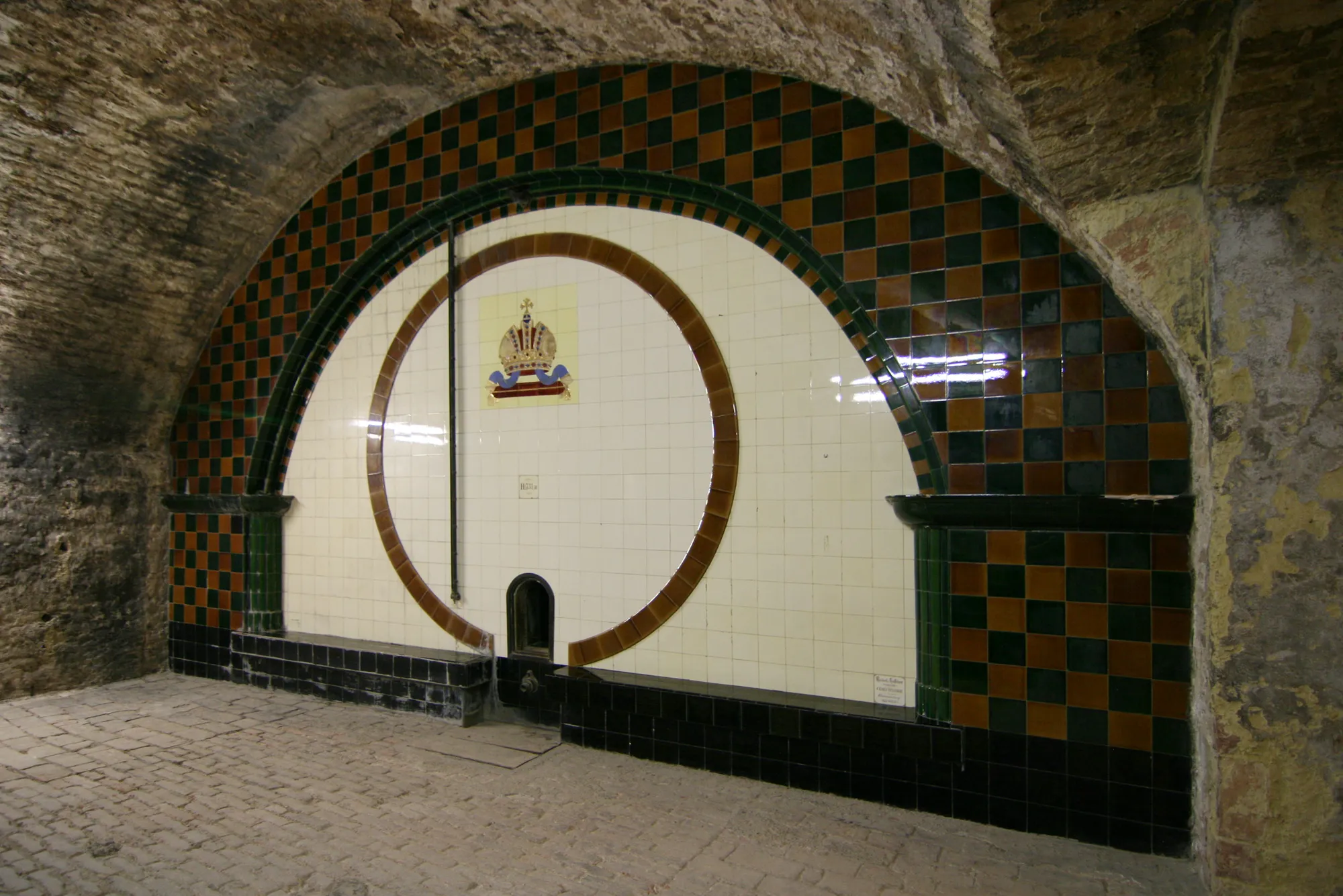 A vaulted Viennese wine cellar, the great oak barrel at its end lit from above.