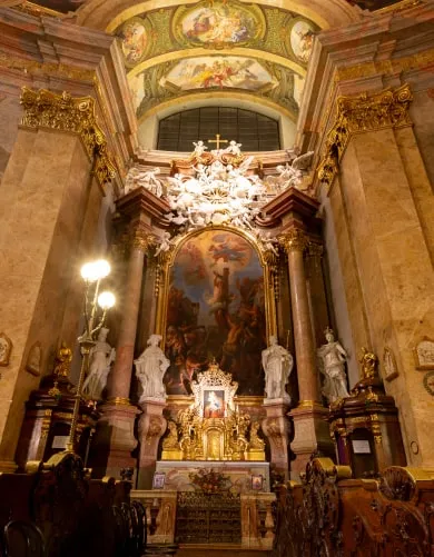 A side altar of the Peterskirche: marble columns, white statues and the painting above them.