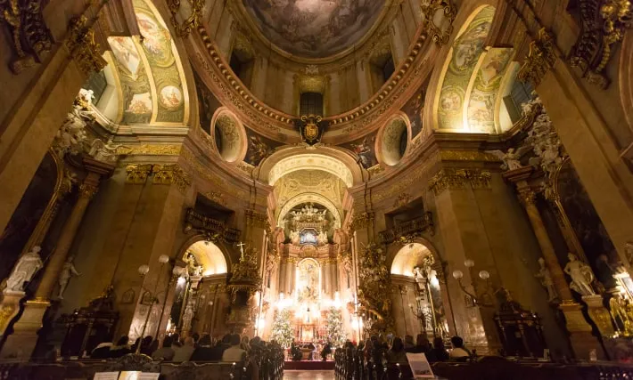 A concert under the dome of the Peterskirche: the audience in the pews and the players lit at the high altar.