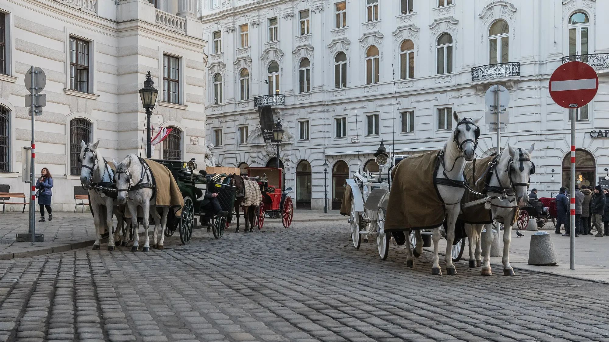 Fiaker carriages waiting on the cobbles of Michaelerplatz, the Hofburg façade behind them.