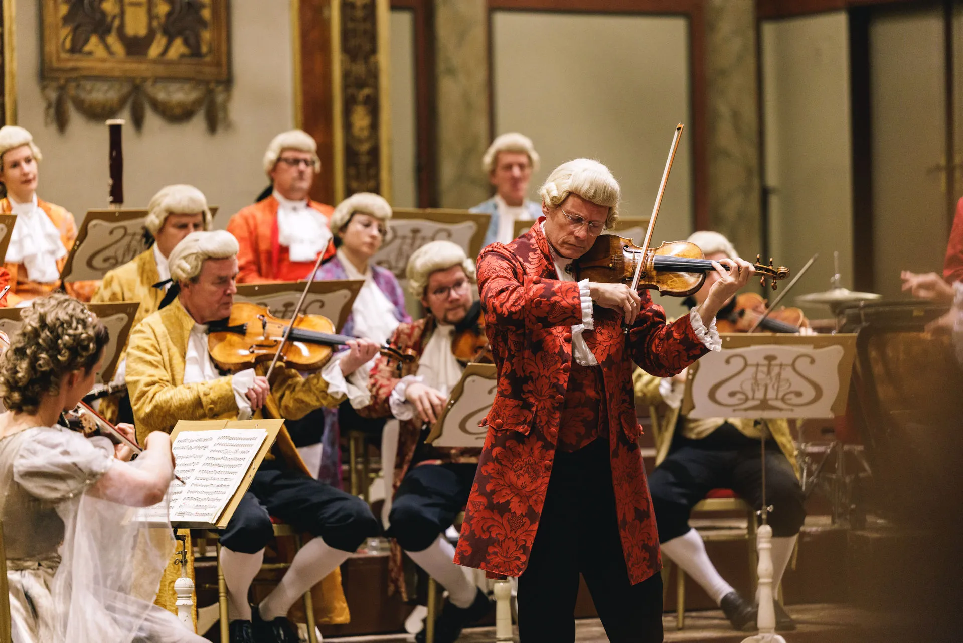 The concertmaster leading the orchestra in historical costume and wig.