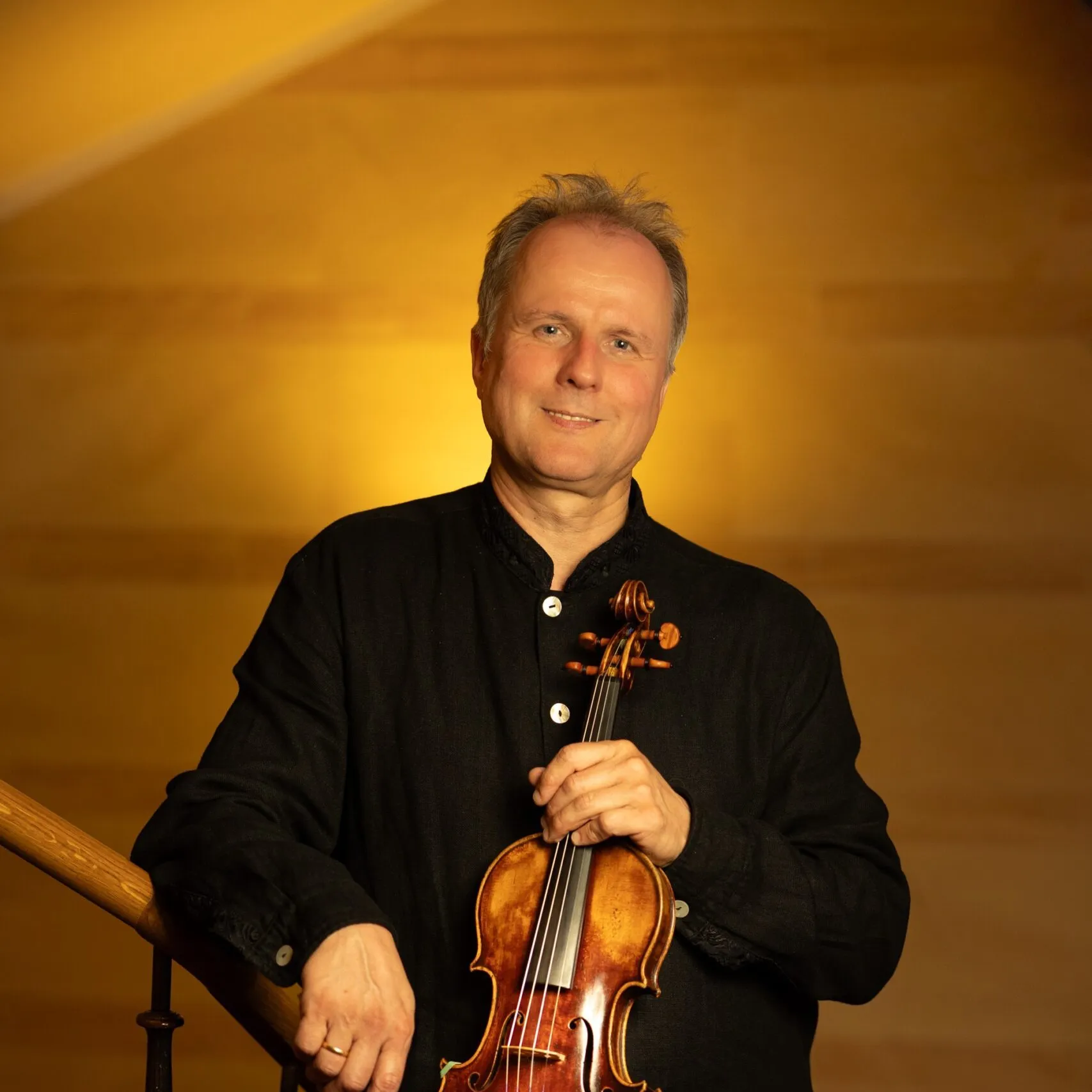 Fritz Kircher holding his violin on a staircase.