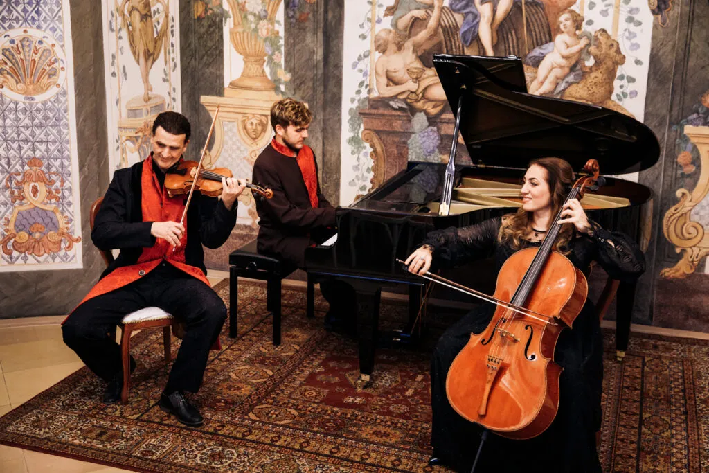 The piano trio at work: violin, grand piano and cello on the hall’s carpet.