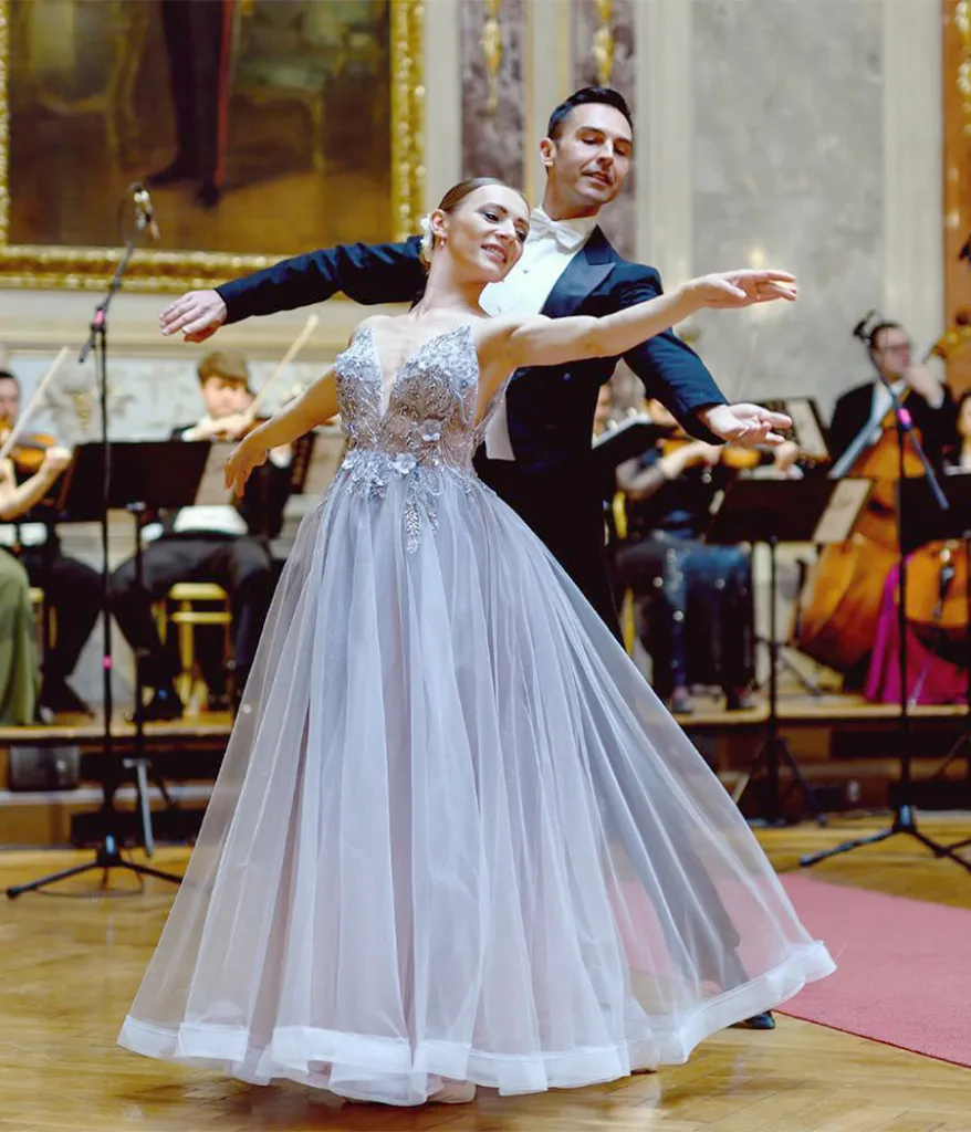 A ballet pair dancing a waltz in front of the orchestra.