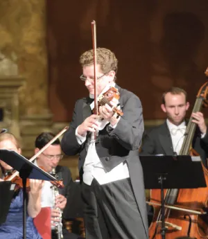 Michal Hudak, concertmaster, playing the violin in front of the orchestra.