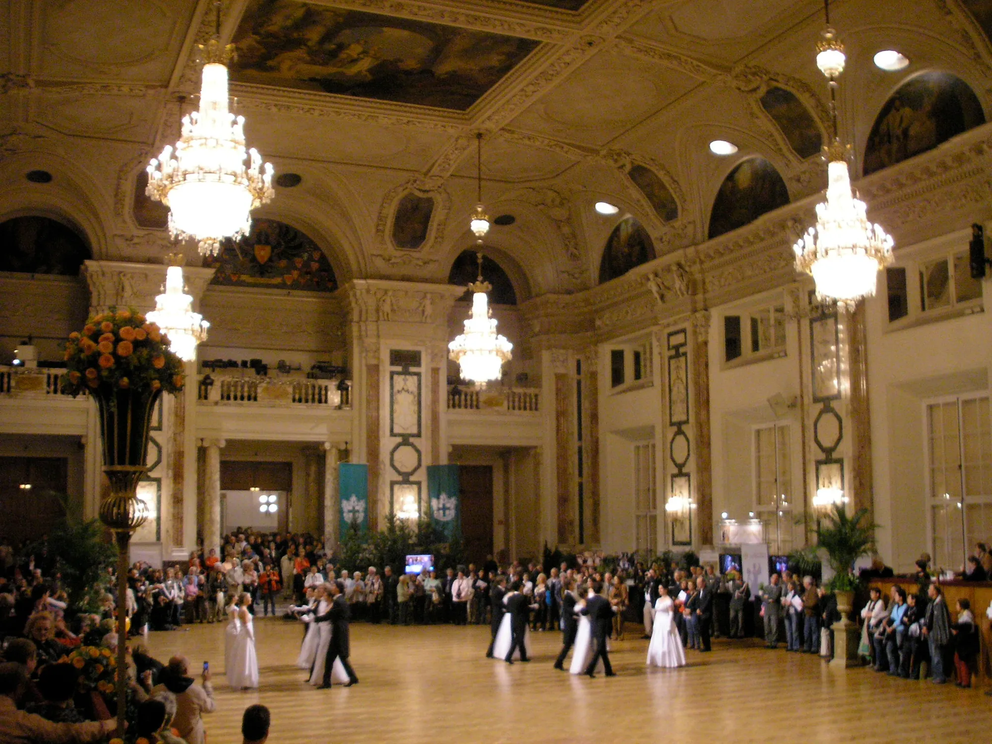 A ball in the Hofburg: couples dancing under the chandeliers while guests watch from the edge of the floor.