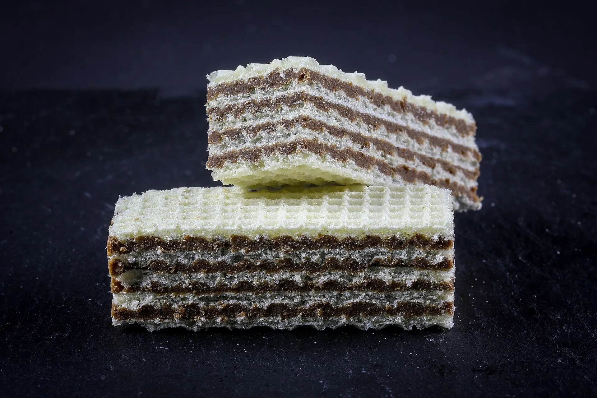 Neapolitan wafers stacked on a dark table, the hazelnut cream showing at the cut