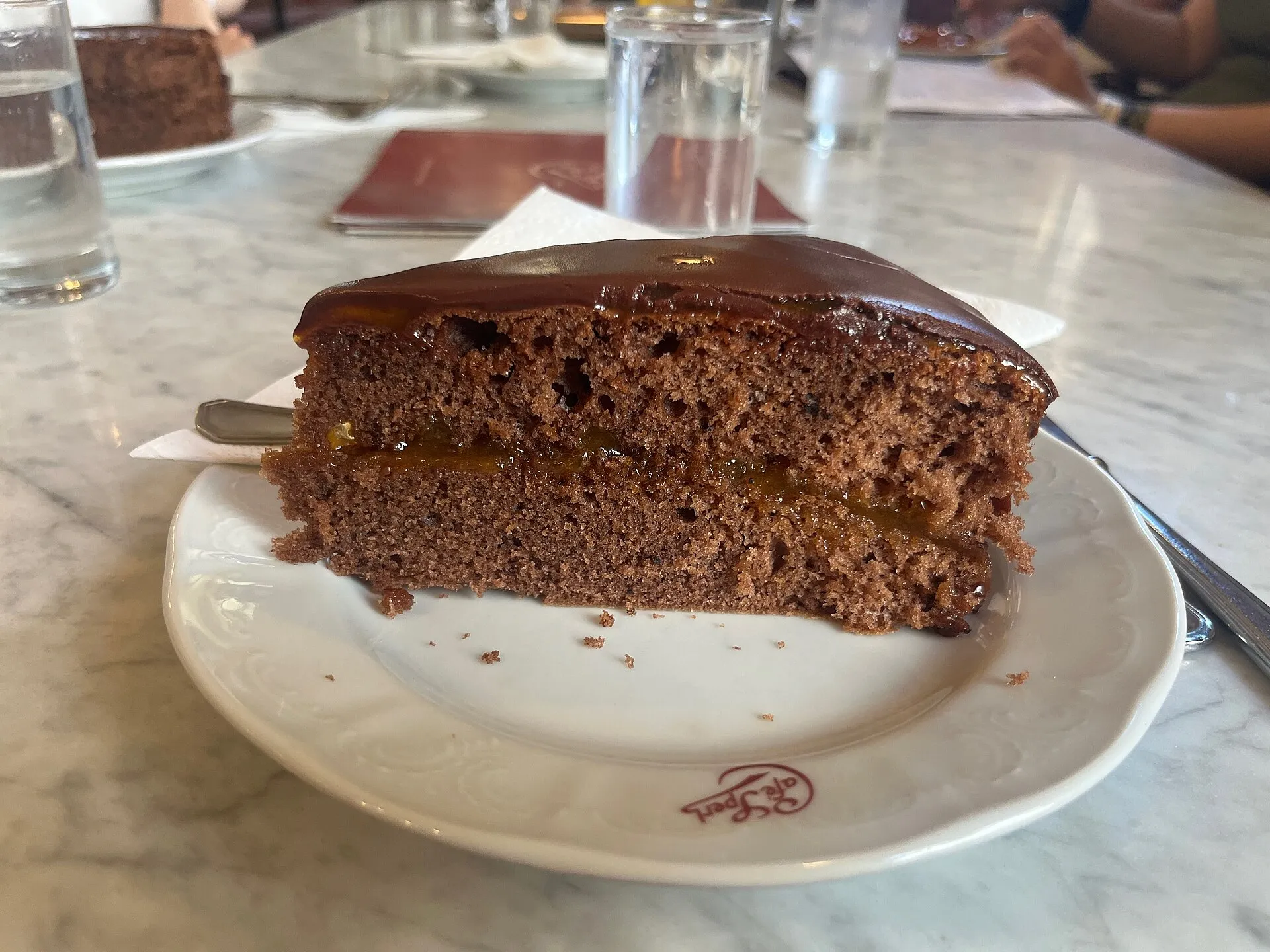 A slice of dark chocolate torte with whipped cream on a marble café table in Vienna