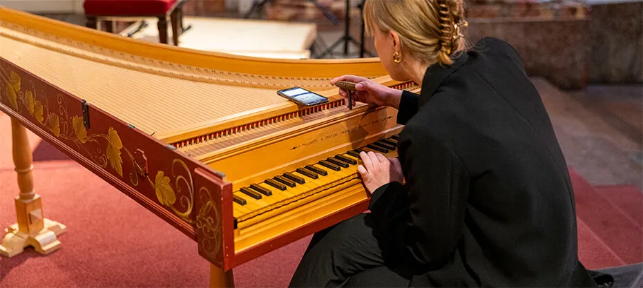 A player tuning the ensemble’s painted harpsichord before the concert.